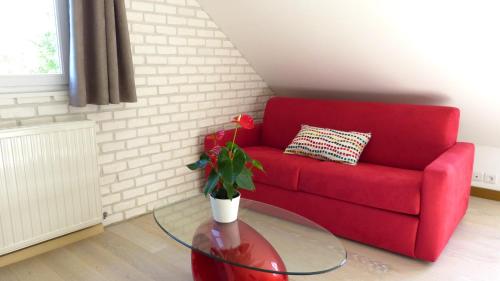 a red couch and a glass table with a potted plant at Millygite Cosy Loft in Milly-la-Forêt