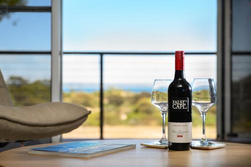 a bottle of wine sitting on a table with two glasses at Lazy Breeze Retreat 31 Beach Crescent, Baudin Beach in Baudin Beach