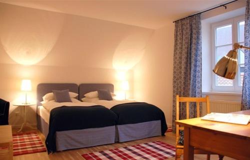 a bedroom with a bed and a desk and a window at Altstadthotel Bauern Bräu Schrobenhausen in Schrobenhausen