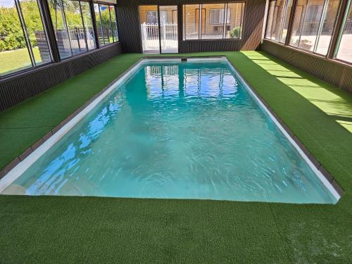 an indoor swimming pool with a green floor and windows at Majestic Motel in Horsham
