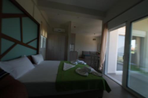 a bedroom with a bed with a green blanket and a window at Thesmos Village in Mýtikas