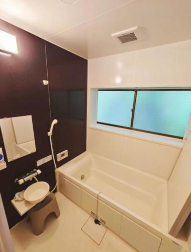 a bathroom with a tub and a toilet and a window at Homestay民泊月読庵 in Tottori