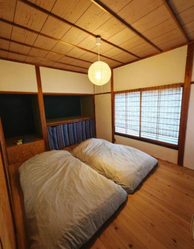 a large bed in a room with a wooden ceiling at Homestay民泊月読庵 in Tottori