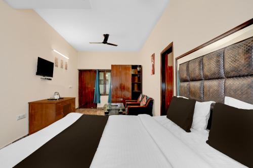 a hotel room with a large bed and a chair at Hotel O Ashtley Hall Dehradun Formerly Daichi in Dehradun