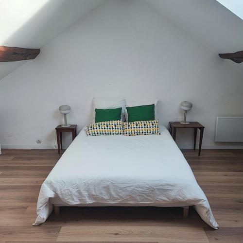 a bedroom with a large white bed with green pillows at Cozy house, small garden and parking, train station on foot in Orgerus