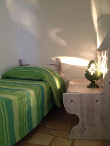 チェーリエ・メッサーピカにあるTrullo Ceglie Messapicaのベッドルーム1室(ベッド1台、テーブルの上にランプ付)