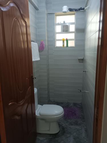 a bathroom with a toilet and a window at 1 bedroom BNB Makutano Meru 06 in Meru