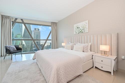 a white bedroom with a bed and a large window at Difc 1 Bd apartment in Park Tower in Dubai