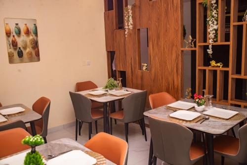 Agape Villa Luxury Apartments في بنين سيتي: مطعم به طاولات وكراسي في غرفة