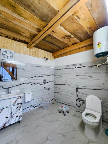 a bathroom with a toilet and a wooden ceiling at Winterfell Cottages - Edition Tandi in Jibhi