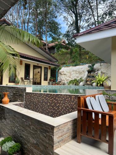 Baan Ton Rak Boutique Resort في كو تشانغ: مسبح في حديقه خلفيه مع منزل