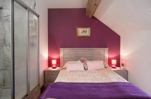 een slaapkamer met paarse muren en een bed met 2 lampen bij les gites du verger in Recey-sur-Ource