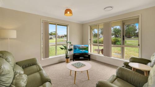 a living room with a couch and a tv at The Coastal Corner in Culburra Beach