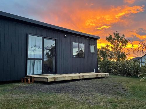 a small house with a deck and a sunset at Watkins Tiny Retreat in Rangiora