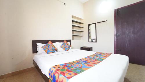 a bedroom with a large white bed with colorful pillows at Varun Residency New in Coimbatore