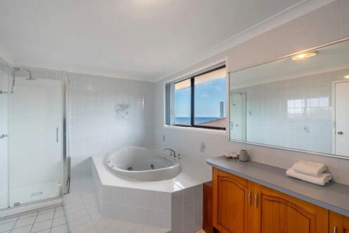a white bathroom with a tub and a sink at Hasta Manyana ocean front villa in Manyana