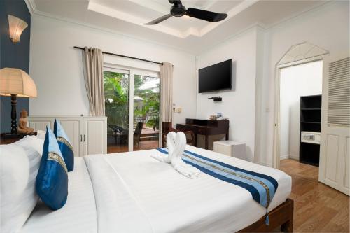 a bedroom with a white bed and a television at Samaya Boutique & Cuisine in Phnom Penh
