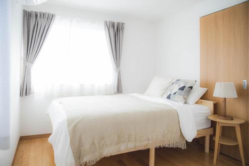 松本Sa one ko松本的卧室里有一张白色的床和一扇大窗户