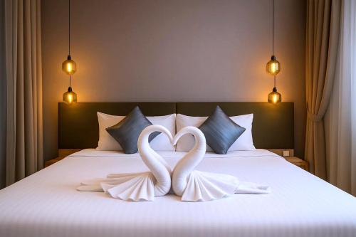 two white swans making a heart shape on a bed at Cormar Suites Kuala Lumpur in Kuala Lumpur