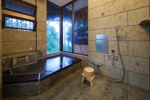 a bathroom with a tub and a shower and a toilet at 熱海絶景温泉宿 kintsugi 宙 in Wada