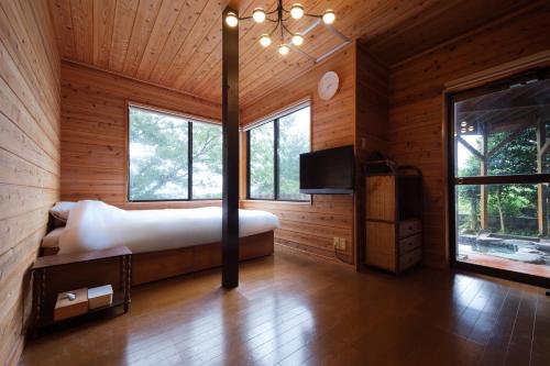 a bedroom in a log cabin with a bed and a tv at 熱海絶景温泉宿 kintsugi 宙 in Wada