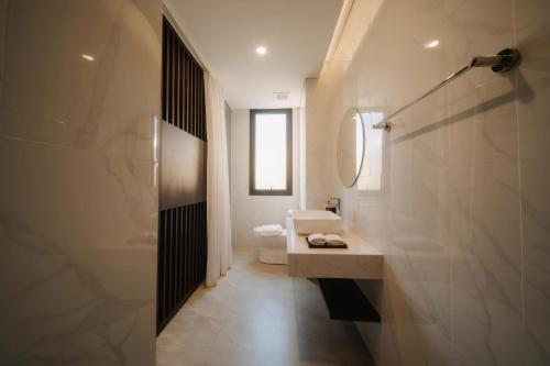 Un baño con inodoro, lavabo y espejo. en Lynntimes Thanh Thủy Wellness Hotel & Resort, en La Phu