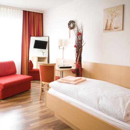 um quarto de hotel com uma cama e uma cadeira vermelha em Hotel Gasthof Pension Riebel em Etzenricht