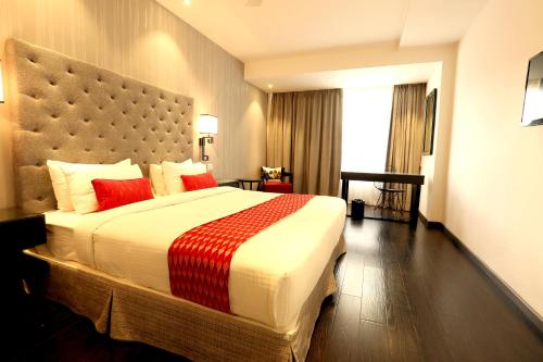 a hotel room with a large bed with red pillows at Hotel Deccan Serai, HITEC CITY, HYDERABAD in Hyderabad