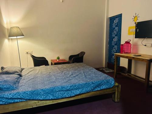 a bedroom with a bed and a desk and chairs at Cozy haven in Auroville