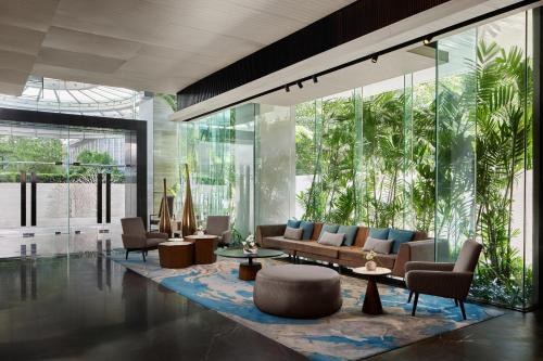 a lobby with couches and tables and glass walls at DoubleTree by Hilton Bangkok Ploenchit in Bangkok