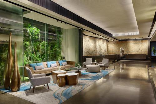 a lobby with couches and tables and a large window at DoubleTree by Hilton Bangkok Ploenchit in Bangkok