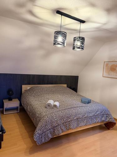 a bedroom with a bed with two towels and two lights at Gîte au secret des vignes in Bergholtz
