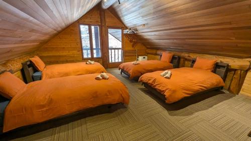 a bedroom with three beds in a log cabin at Hakuba Loghouse in Hakuba