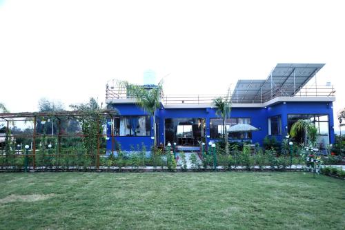 una casa blu con recinzione e cortile di The Tiger Waterfront Resort a Mādho Tānda