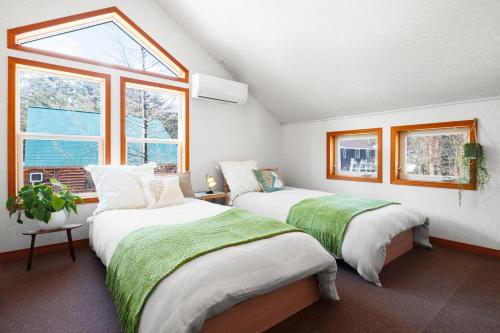 two beds in a room with two windows at Chalet GOROU in Hakuba