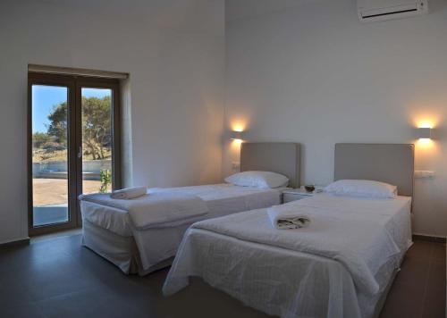 2 łóżka w pokoju hotelowym z oknem w obiekcie Anny's Homes w mieście Kountoura Selino