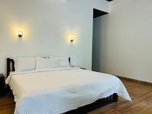 Un dormitorio con una gran cama blanca con almohadas blancas. en Marari Beach Cleetus Homestay, en Alleppey