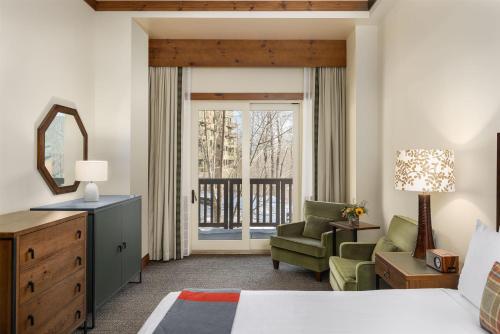 a bedroom with a bed and a chair and a window at The Lodge at Spruce Peak, a Destination by Hyatt Residence in Stowe