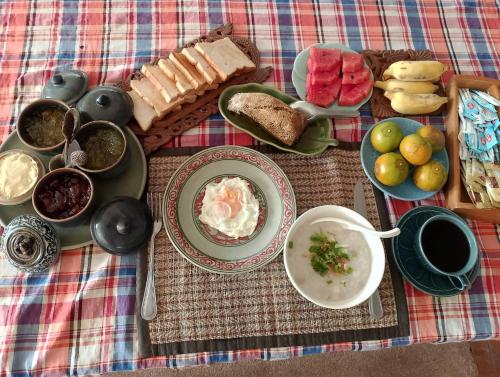 einen Tisch mit Teller und Schüsseln mit Essen und Brot in der Unterkunft ออร์คิดไฮบิสคัส เกสท์เฮ้าส์ in Sukhothai