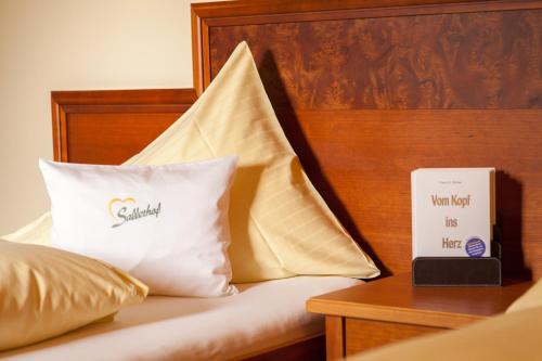 a bed with two pillows and a book on it at Garten - Hotel Sallerhof in Salzburg