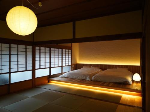 a bedroom with a bed with lights and windows at Newopen 一棟貸切宿YUNOWA 車3台駐車可 6名様まで同料金 in Nagato