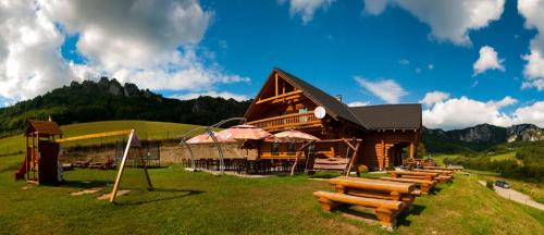 a log cabin with a bunch of benches in front of it at Koliba Pod Skalami in Súľov-Hradná