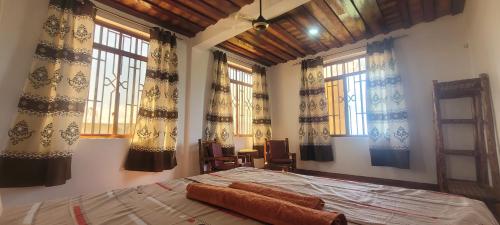 a bedroom with a bed in a room with windows at Villa Katerina-Zanzibar Apartment Paje in Paje