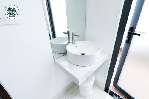 ein weißes Badezimmer mit Waschbecken und Spiegel in der Unterkunft OMEGA HOUSE Thốt Nốt in Thốt Nốt