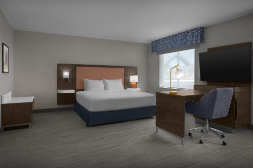 Hampton Inn & Suites By Hilton Wheat Ridge Denver West في ويت ريدج: غرفة فندقية تحتوي على سرير ومكتب وتلفزيون