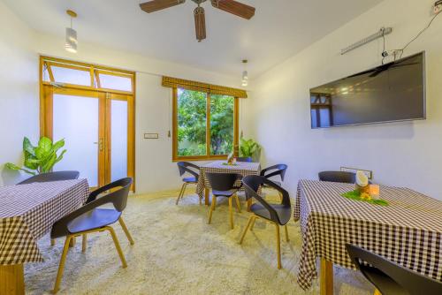 a dining room with tables and chairs and a flat screen tv at Ameera Maldives in Dhiffushi