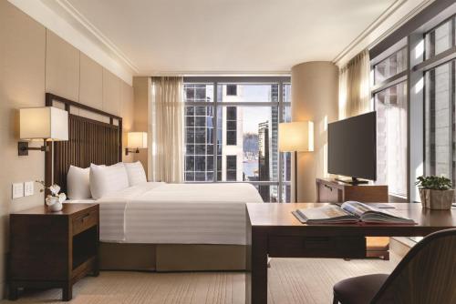 a hotel room with a bed and a desk and a television at Hyatt Vancouver Downtown Alberni in Vancouver