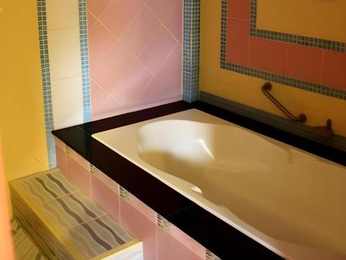 The Great Hotel & Resort في Ban Rong Chang: حوض استحمام في الحمام مع بلاط وردي وأسود