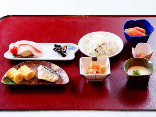 ein Tablett mit Tellern voller Essen auf einem roten Tisch in der Unterkunft 黒姫高原ホテル in Shinano