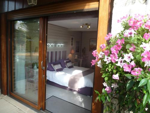 a room with a bed and a glass door with flowers at Les Bruyères du Mont in Céaux